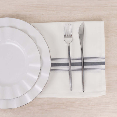 Elegant table setting with white plates, silver cutlery, and a striped napkin.