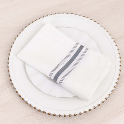White napkin with gray stripes on a decorative plate.