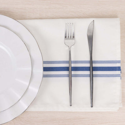 White dinner plate, fork, and knife on a table with a blue-striped napkin.