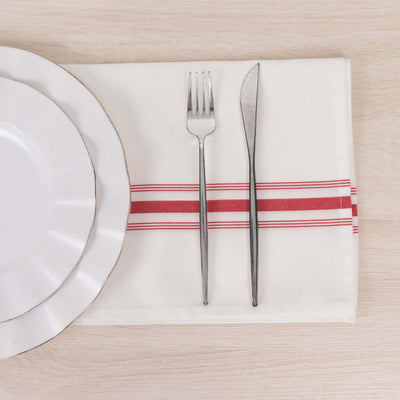 Silver fork and knife on a red-striped napkin with a white plate