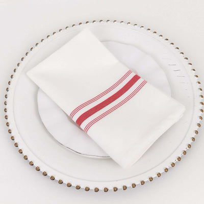 White napkin with red stripes on a decorative plate.