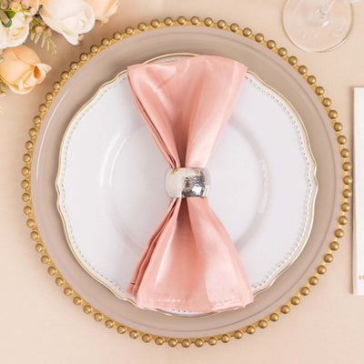Elegant pink napkin with silver ring on a decorative plate setting.