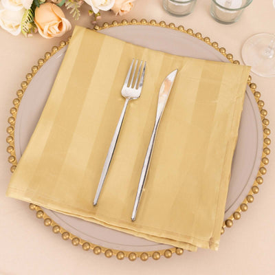Gold striped napkin with fork and knife on a decorative plate.