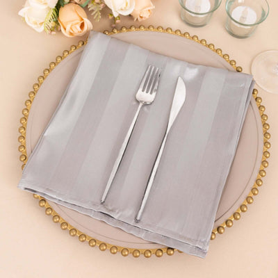 Gray striped napkin with fork and knife on an elegant table setting.