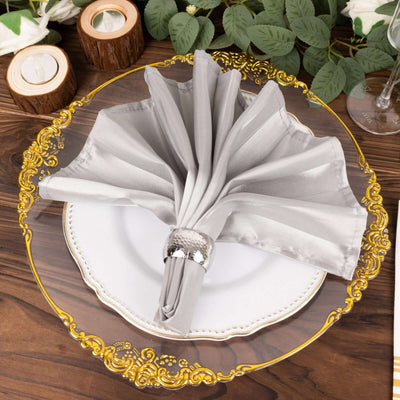 Elegant gray napkin elegantly folded on a decorative plate with a silver napkin ring.