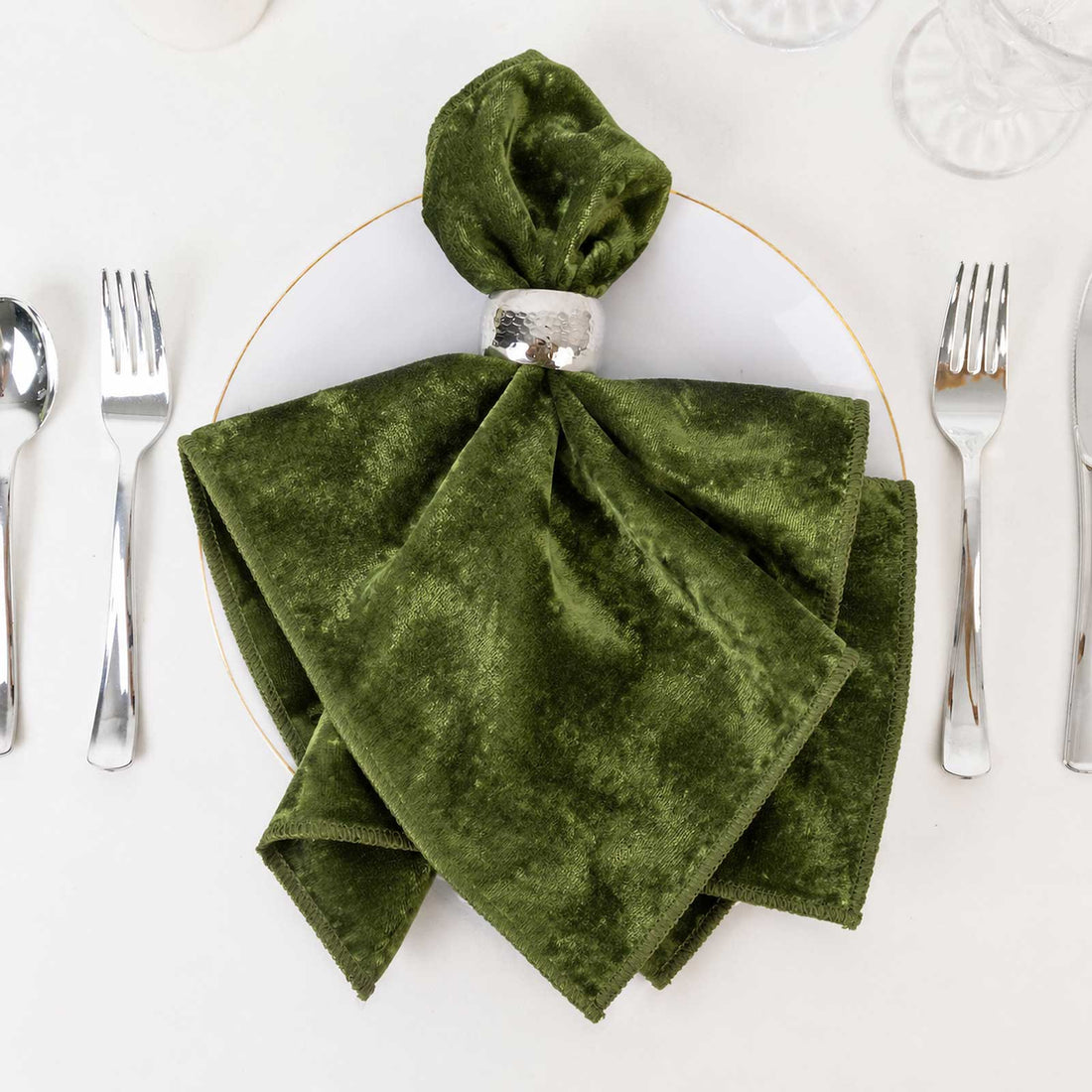 Green velvet folded napkin with silver napkin ring on elegant table setting