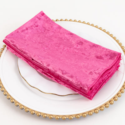 Pink velvet napkin stacked on a decorative plate.