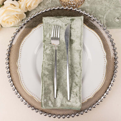 Elegant dinnerware set with a silver fork and knife on a green velvet napkin.