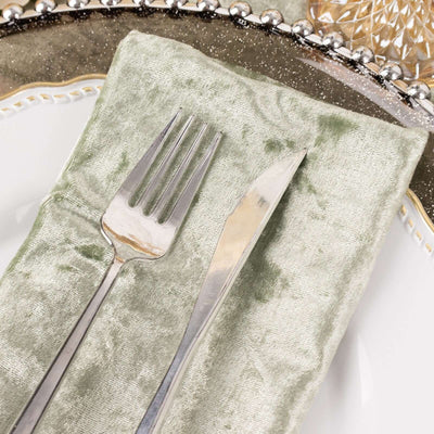 Silver fork and knife on a soft green napkin atop an elegant plate.