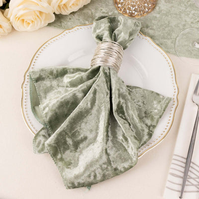 Elegant green velvet napkin with silver napkin ring on a decorative plate.