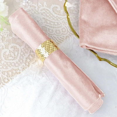 Pink satin napkin with gold ring holder on lace table setting.