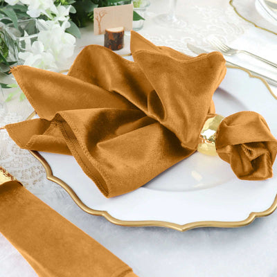 Elegant brown silk napkin elegantly arranged on a white plate with gold trim.