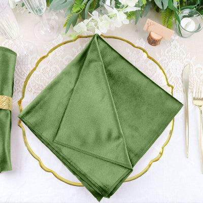 Green velvet napkin elegantly placed on a gold-rimmed plate.