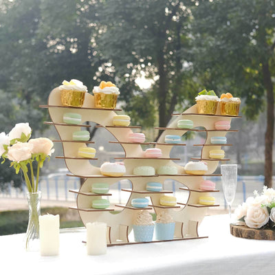 Elegant cupcake stand with pastel treats and floral decor at an outdoor event.