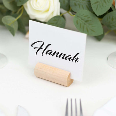 Place card with the name Hannah on a wooden holder surrounded by greenery.