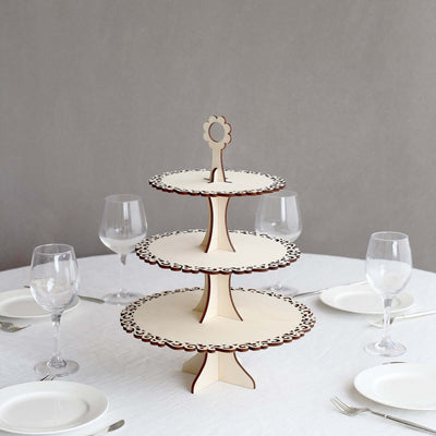 Three-tiered wooden cake stand with intricate cutout design.