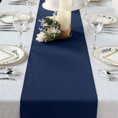 Navy blue table runner on a decorated dining table with flowers and candles.