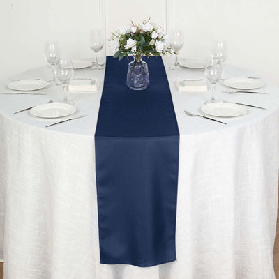 Navy table runner on a white table with elegant dinnerware and floral centerpiece.