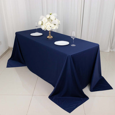 Navy tablecloth with white plates and floral centerpiece on a banquet table.