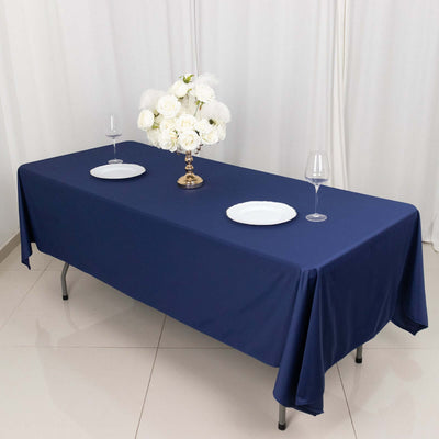 Navy blue tablecloth on a dining table with white plates and a floral centerpiece.