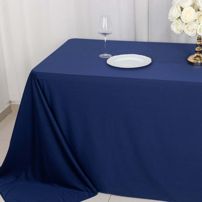 Navy tablecloth with a plate and wine glass on a dining table setup.