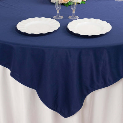 Navy blue tablecloth draped over a table with white plates on top.