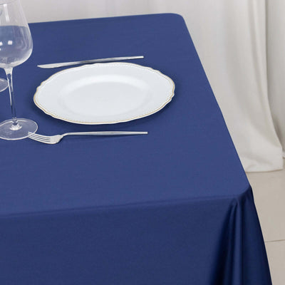 Navy tablecloth set with a white plate and cutlery on a table.
