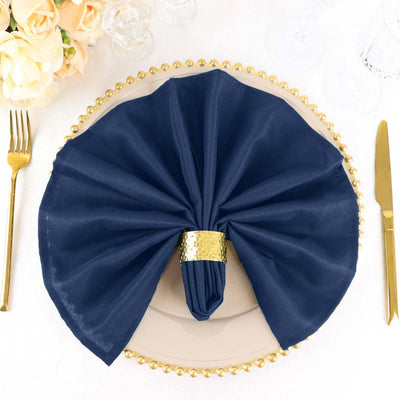 Elegant navy napkin with gold ring on a decorative plate.