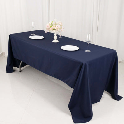 Navy blue tablecloth on a dining table set with plates and glasses.