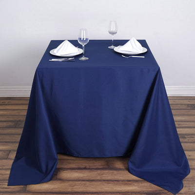 Navy blue tablecloth on a dining table set for two with plates and glasses.