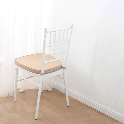 White chair with beige cushion against a plain backdrop.