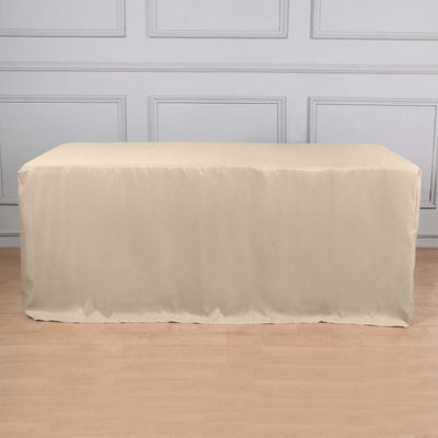 Beige table cover on a wooden floor with a decorative wall behind it.