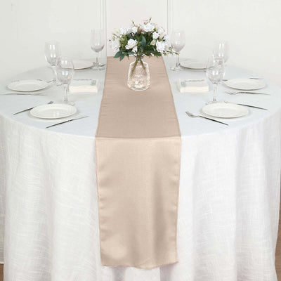 Elegant beige table runner on a round table set for dining.