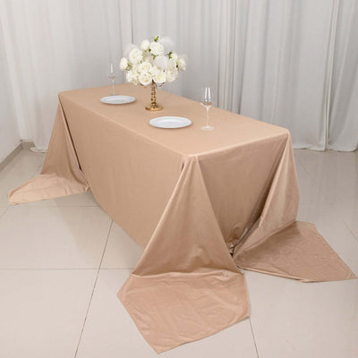 Elegant beige tablecloth draped over a table with a floral centerpiece and wine glasses.