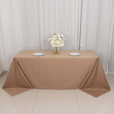 Elegant beige tablecloth with floral centerpiece and dinnerware setup.