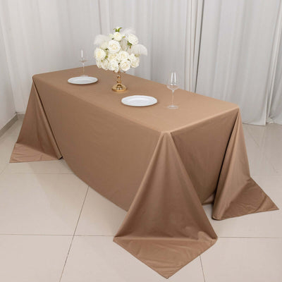 Elegant beige tablecloth draped over a dining table with floral centerpiece and dinnerware.