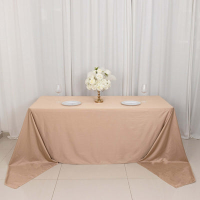 Elegant beige tablecloth with floral centerpiece and dinnerware setup.