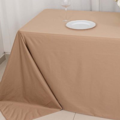Beige tablecloth draped elegantly over a table with a plate and glass.