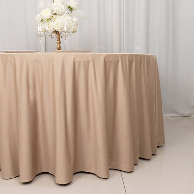 Beige tablecloth on a round table with a floral centerpiece.