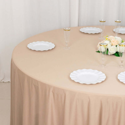 Elegant round table set with white plates and floral centerpiece.