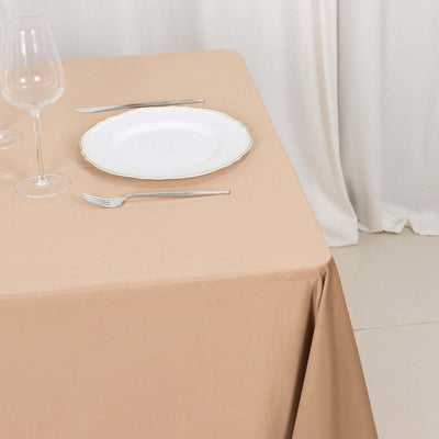 Elegant beige tablecloth set with wine glasses and a white plate.