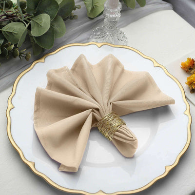 Beige napkin elegantly folded on a decorative plate with gold trim.