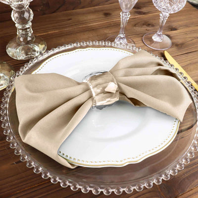 Elegant beige napkin with crystal ring on a decorative plate.