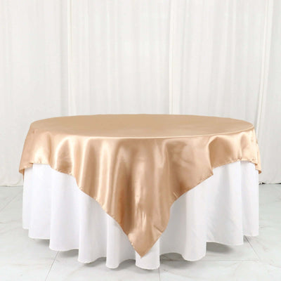 Gold satin tablecloth draped over a round table in a studio setting