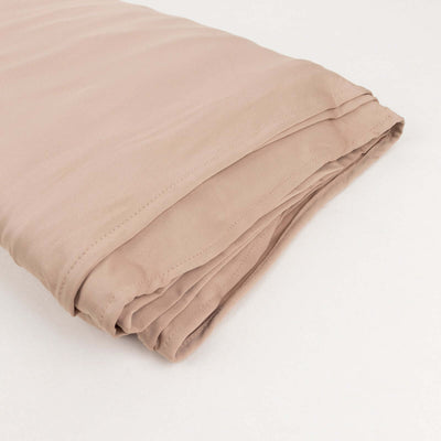 Folded beige fabric showcasing smooth texture on a plain backdrop.