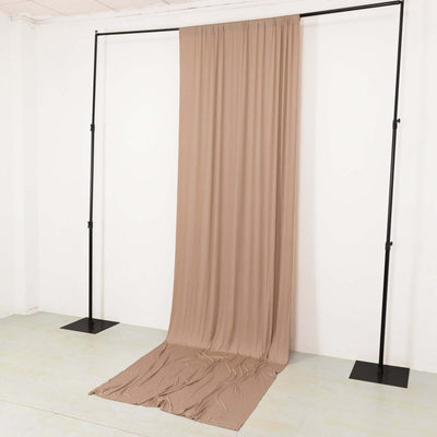 Beige fabric draped on a black backdrop stand in a minimalist studio setting.