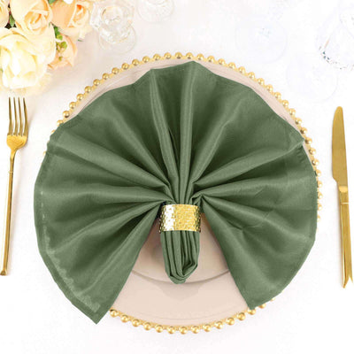 Elegant green napkin with gold ring on a decorative plate.