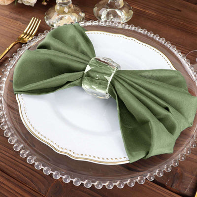 Green satin napkin elegantly tied on a white plate with a crystal napkin ring.