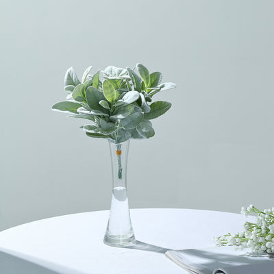 Artificial greenery bouquet in a clear glass vase.
