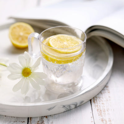 Refreshing lemon water in a clear glass with lemon slices and a flower.